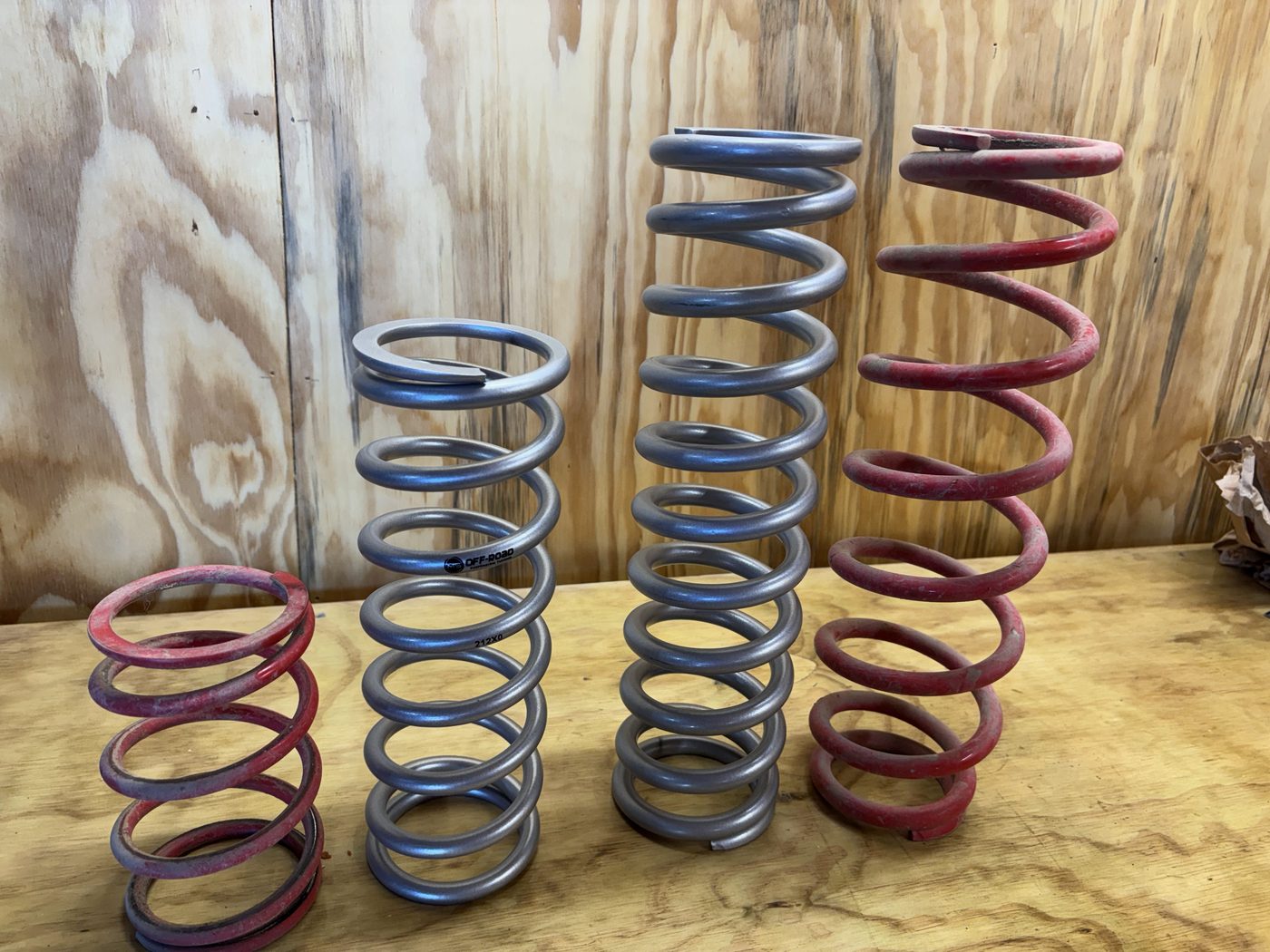 Four aftermarket springs of different rates and lengths lined up side by side